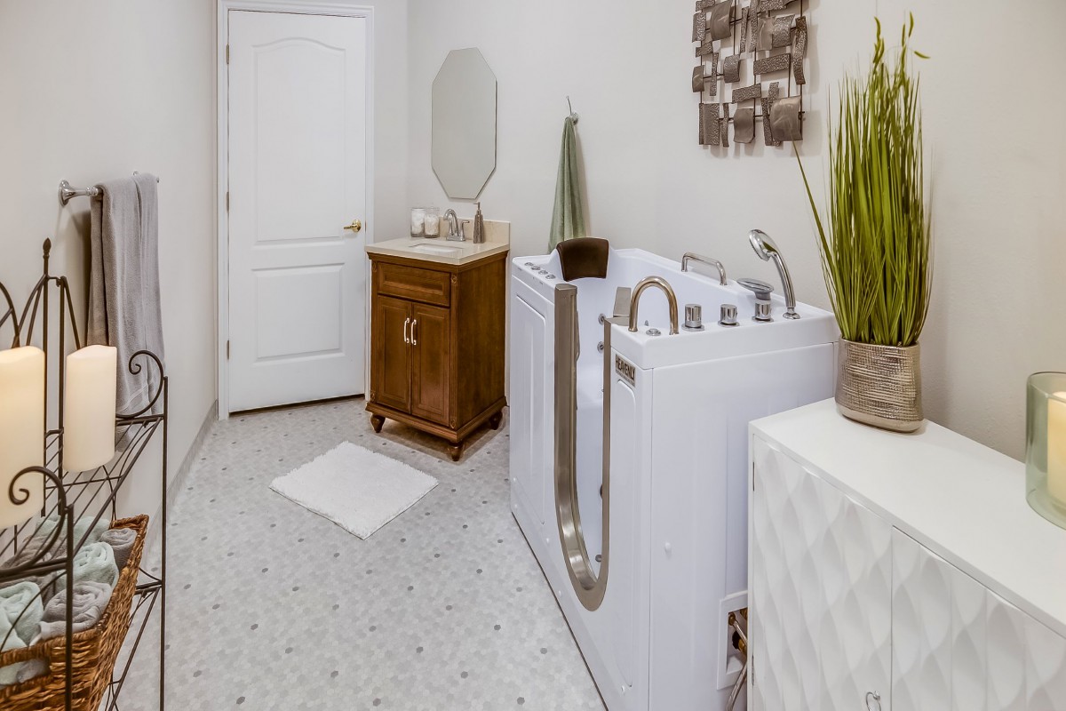 A modern bathroom featuring a walk-in tub and a wooden vanity with a mirror.