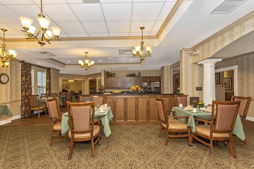 A cozy dining area with elegant chandeliers and neatly arranged tables.