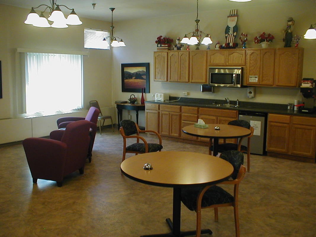 A cozy kitchen and dining area with wooden cabinets, tables, and comfortable seating.