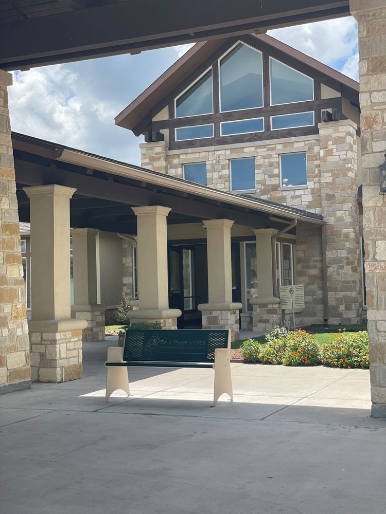 A building with a stone facade, featuring an entrance with columns and a covered walkway.