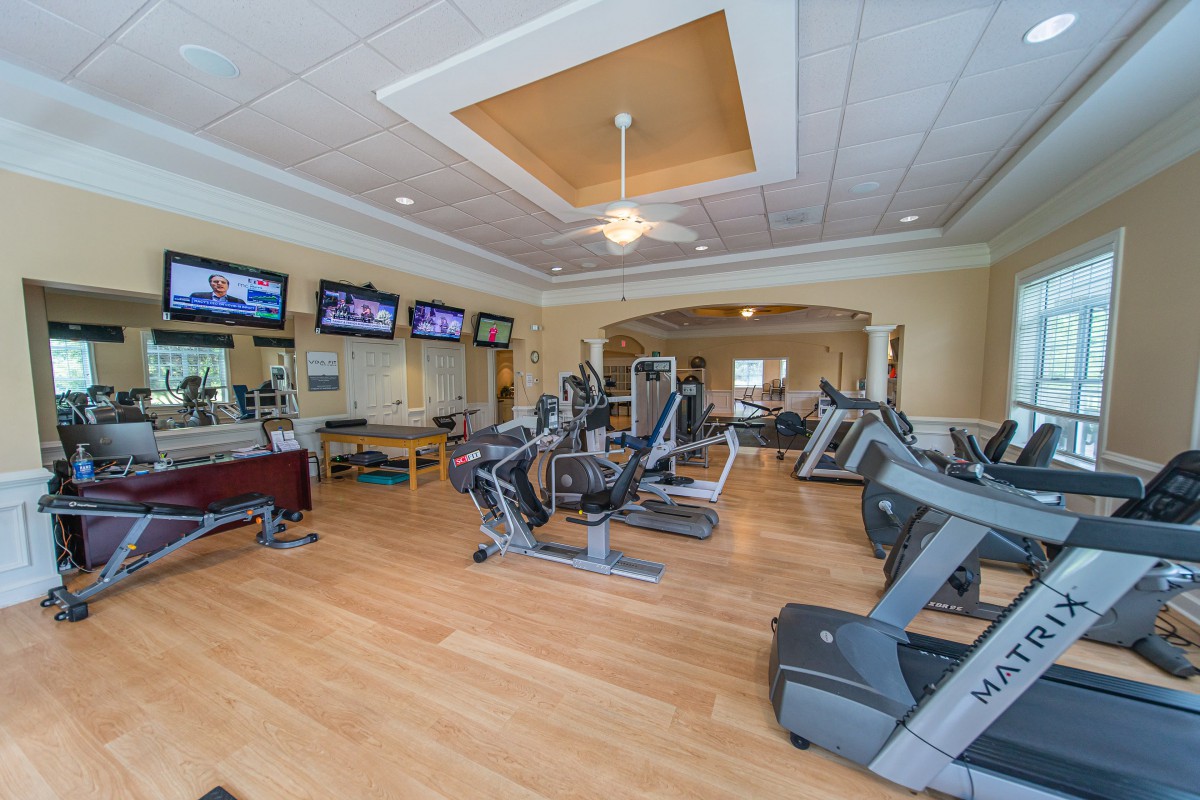 A modern gym equipped with treadmills, exercise bikes, and televisions for entertainment.