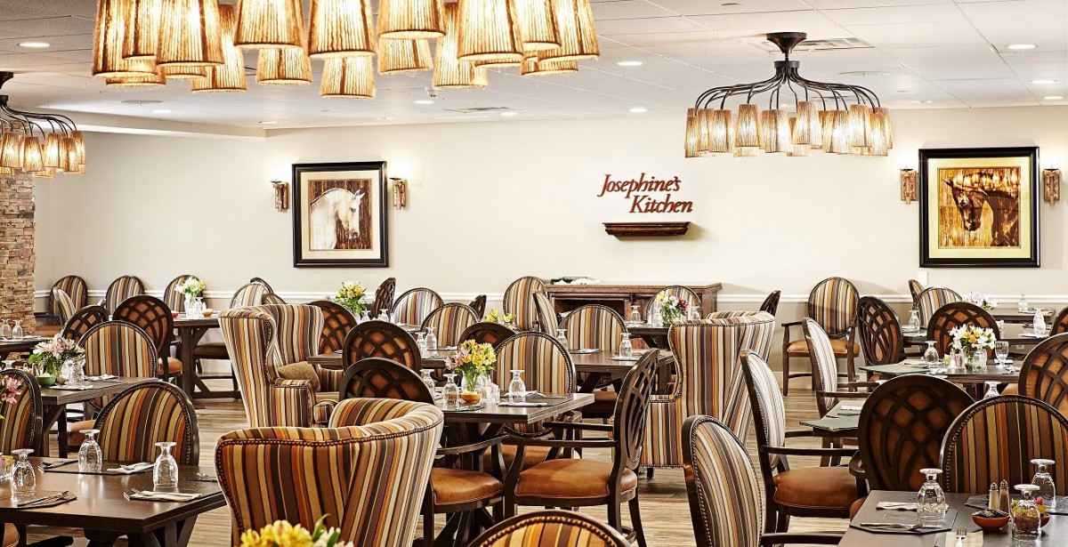 A well-lit restaurant dining area with striped chairs and elegant lighting fixtures.