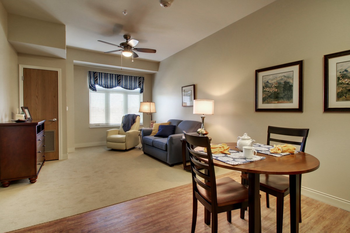 A cozy living and dining area featuring a comfortable sofa, a well-set dining table, and ample lighting.