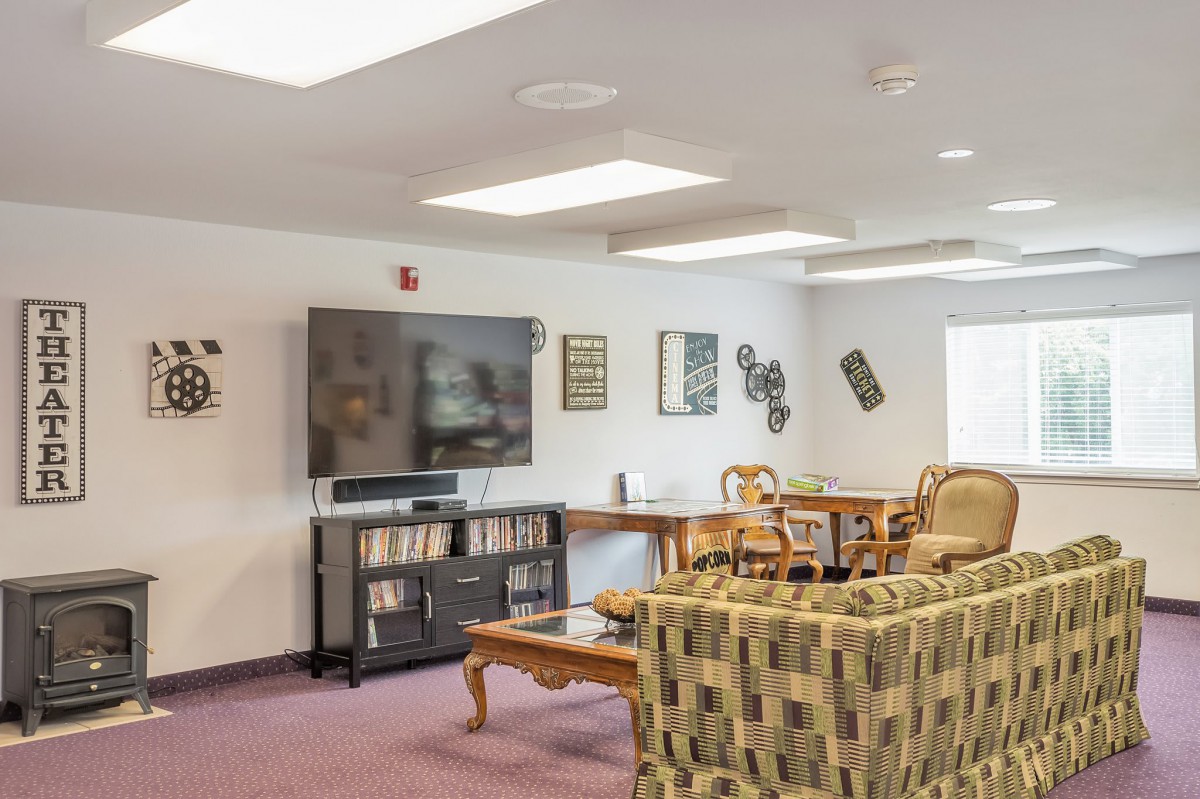 A cozy lounge area with a large television, seating, and decorative elements.