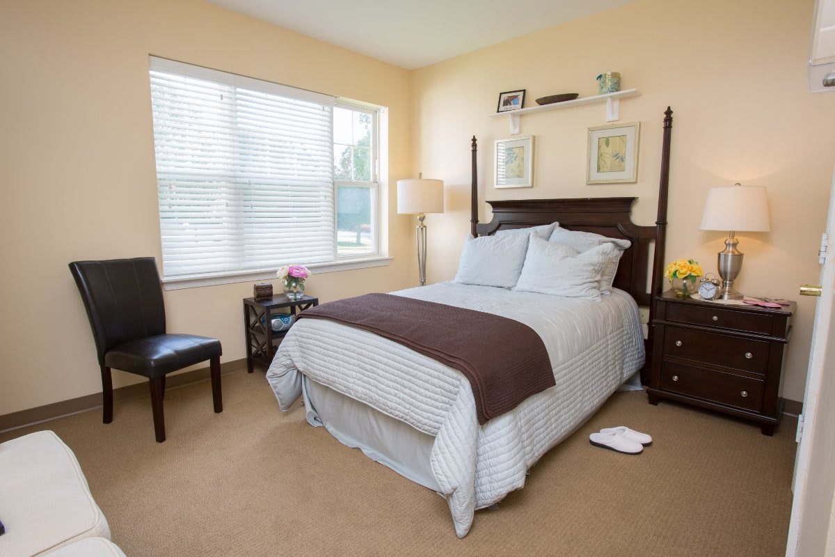A cozy bedroom with a neatly made bed, bedside tables, and a window letting in natural light.