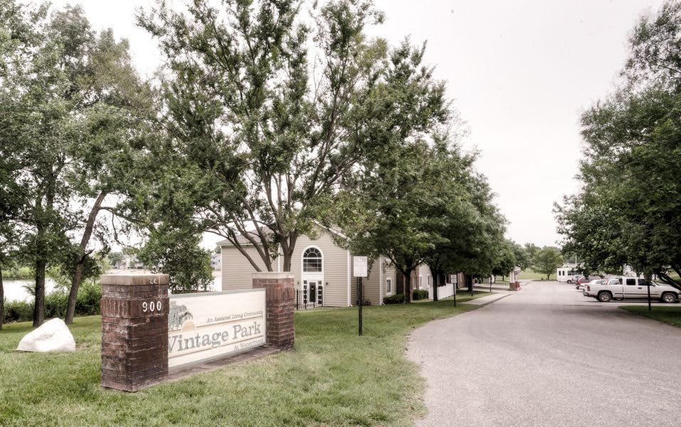 Entrance to a residential apartment complex lined with trees and a driveway.