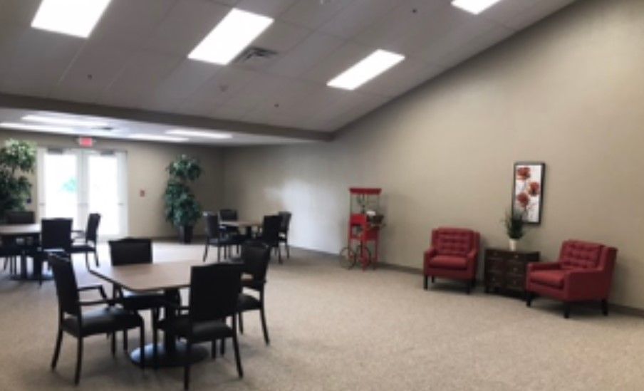 A spacious office area with tables and chairs, featuring a popcorn machine and a red armchair.