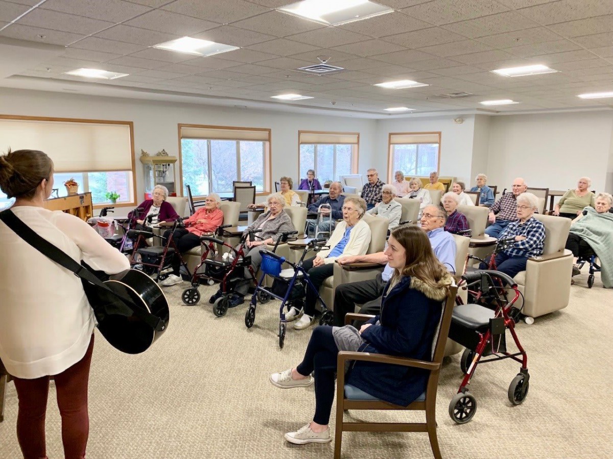 A group of senior citizens gather for a community meeting indoors.