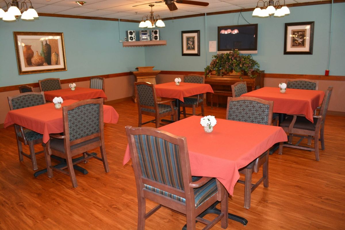 An empty dining area with tables covered in red tablecloths.