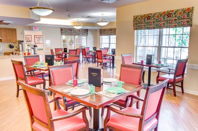 A well-arranged dining area with neatly set tables and red chairs, ready for service.