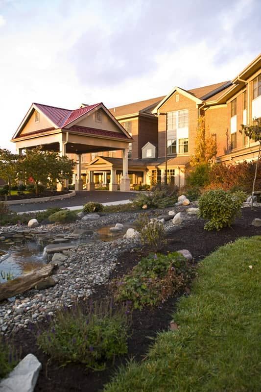 A scenic view of a hotel entrance surrounded by well-maintained gardens.