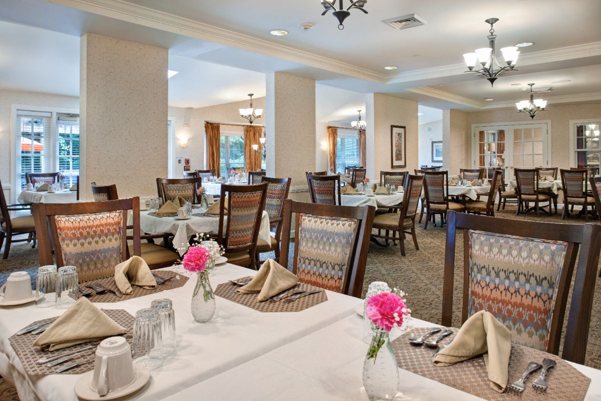 A well-decorated dining area featuring tables with floral centerpieces and neatly arranged table settings.