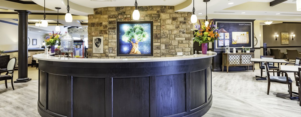 A modern reception desk with artwork and flowers, featuring stylish lighting.
