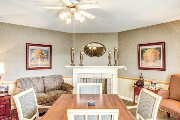A cozy living and dining area featuring a wooden table, chairs, sofa, and a decorative fireplace.