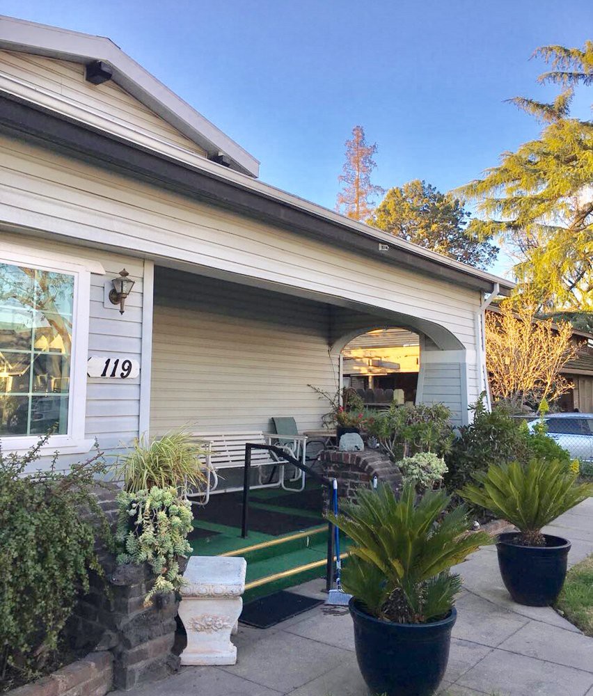 A cozy residential home with a porch adorned with plants.