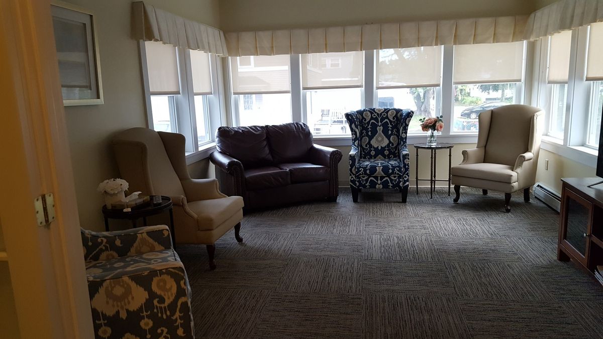 A cozy living room with various chairs and a sofa near large windows.
