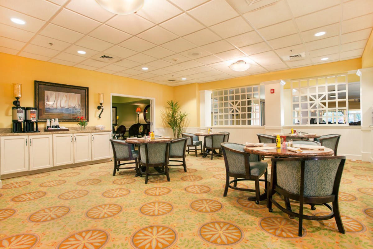 A cozy dining area with neatly arranged tables and chairs, warm lighting, and elegant decor.