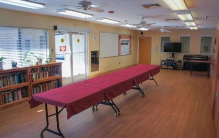 A conference room with a long, red-covered table, whiteboards, and a television.
