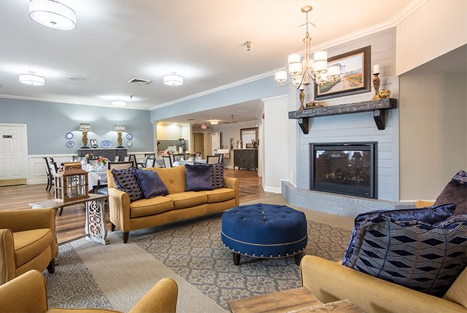 A stylish living room with yellow sofas, a blue ottoman, and a cozy fireplace.