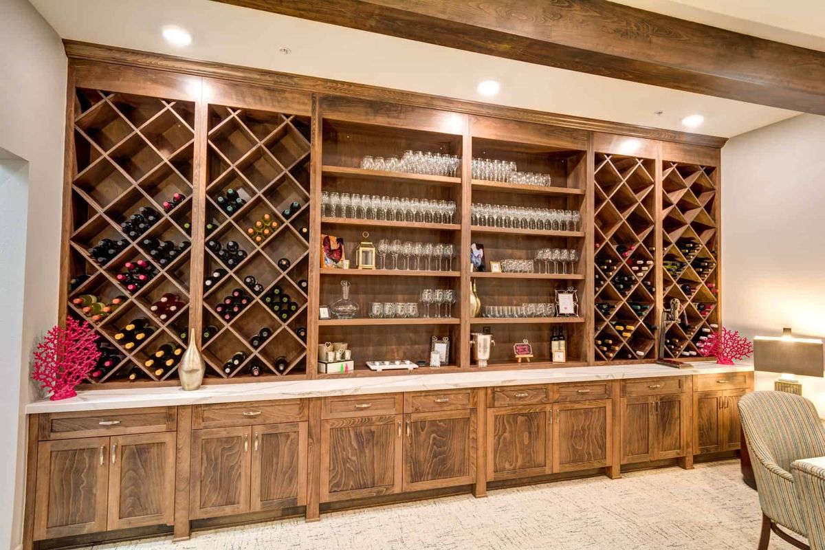 A beautifully designed wine cellar with wooden shelves, featuring a collection of wine bottles and glasses neatly arranged.