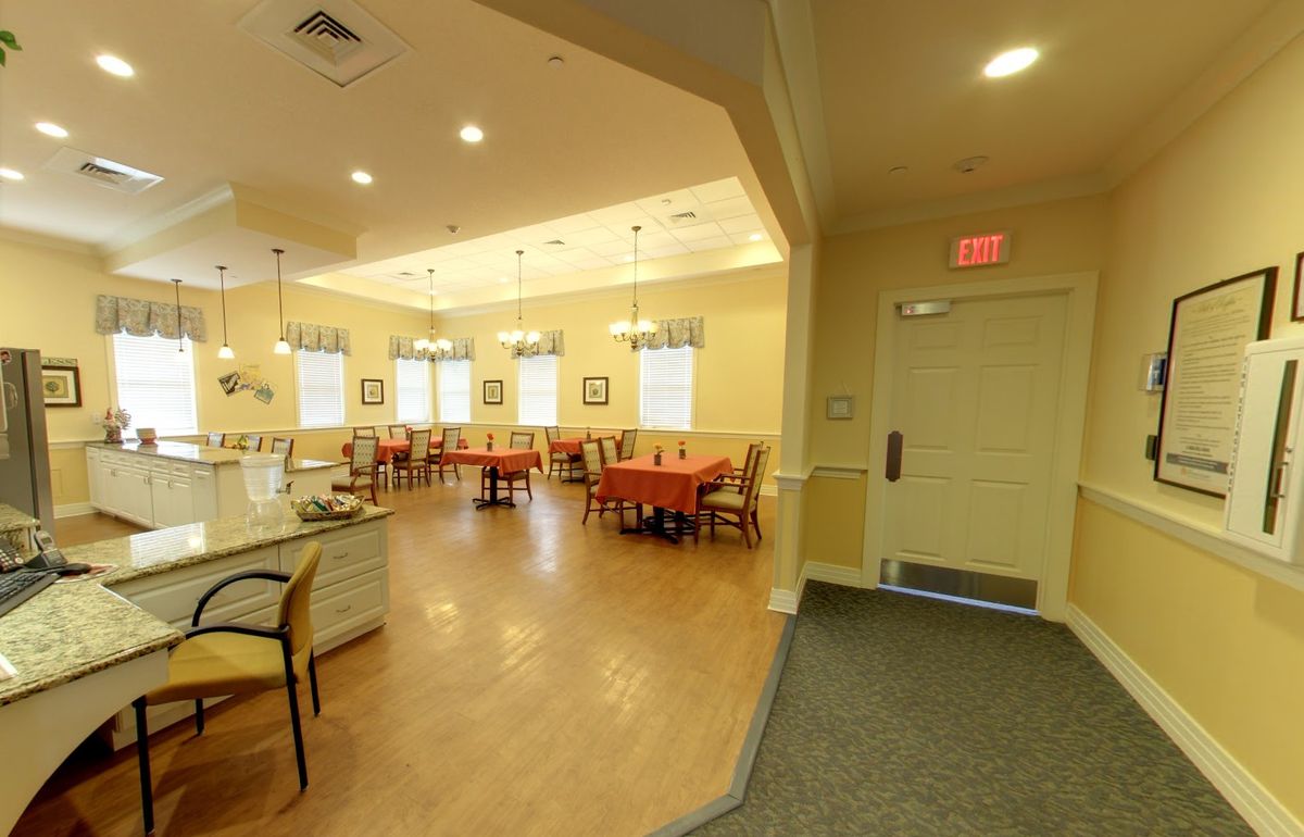 A warmly lit dining area with wooden floors, tables, and chairs set up for guests.