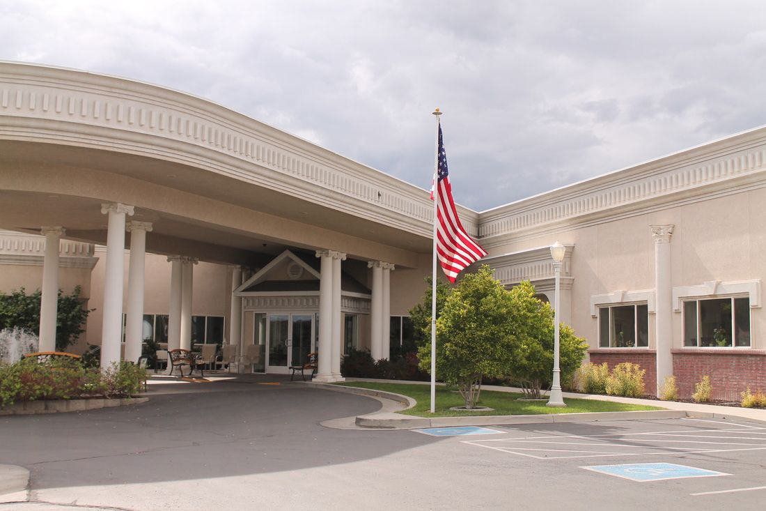 A building entrance with a prominent American flag flying on a cloudy day.