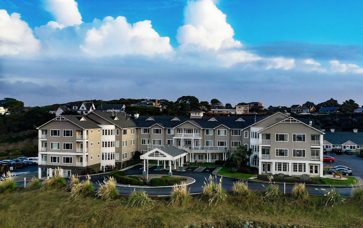 A residential apartment complex under a blue sky with fluffy clouds.