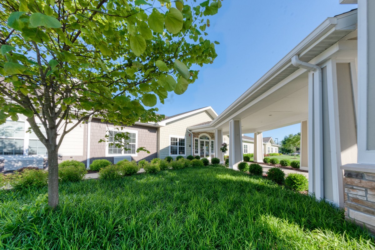 A modern building with a landscaped entrance, surrounded by lush greenery.