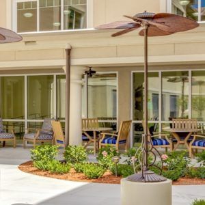 An inviting outdoor patio area with wooden furniture and umbrellas in front of a modern building.