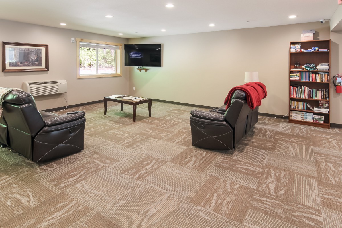 A cozy living room with a TV, sofas, and carpeted flooring.
