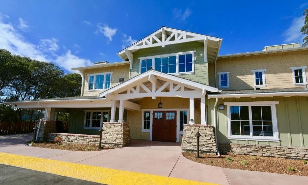 A modern two-story house with a stone facade and large windows under a clear blue sky.