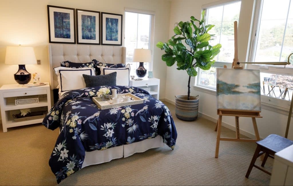 A cozy bedroom featuring a navy floral bedding set, potted plant, and framed artwork on the walls.
