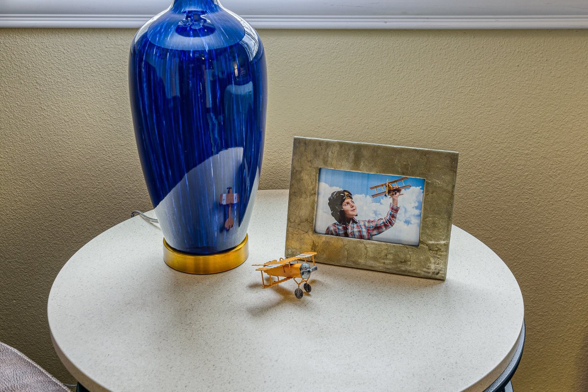 A decorative setup with a blue vase, a photo frame, and a toy airplane on a table.