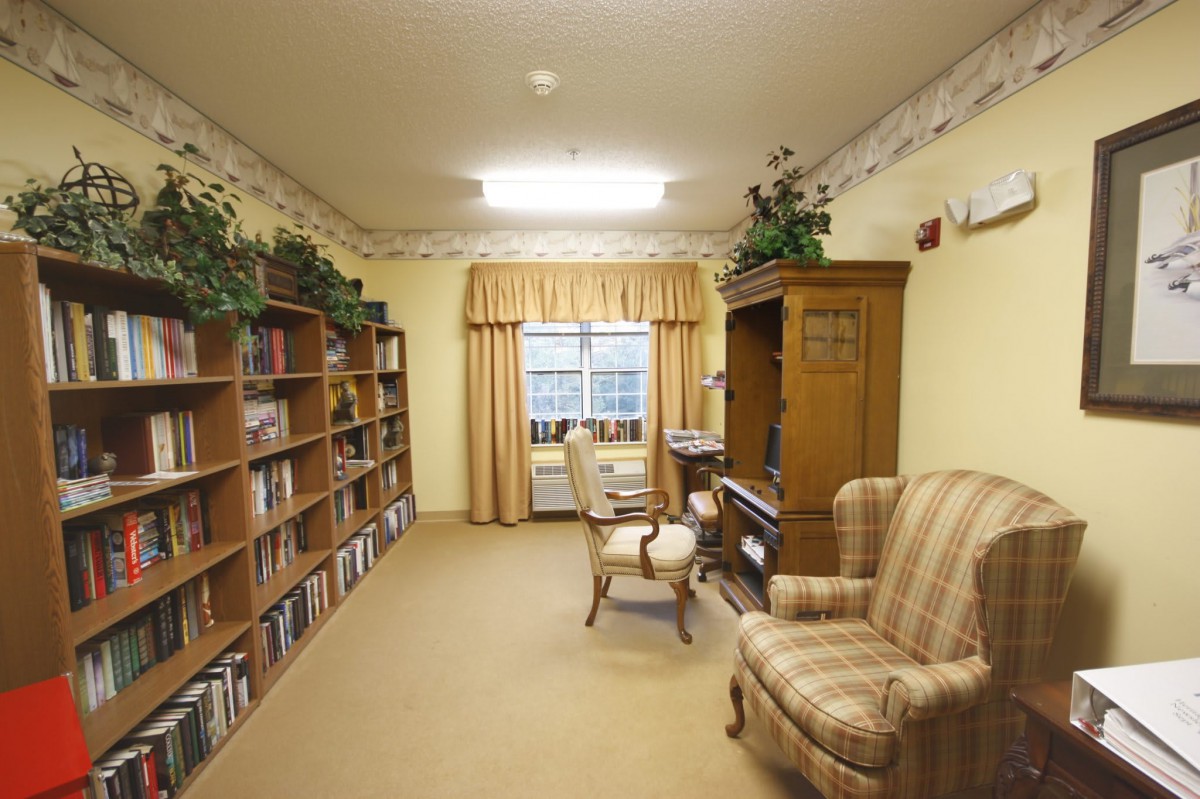 A cozy home library with bookshelves, a desk, and an armchair.
