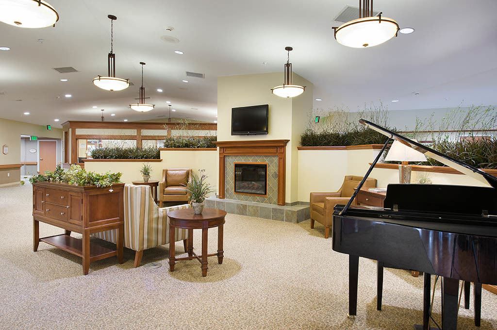 A modern lounge area featuring a piano, comfortable seating, and a cozy fireplace.