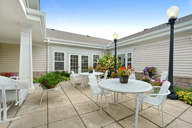 A cozy courtyard with white patio furniture and vibrant plants.