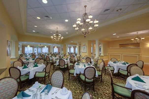 An elegant dining room with neatly arranged tables and chairs, decorated with chandeliers.