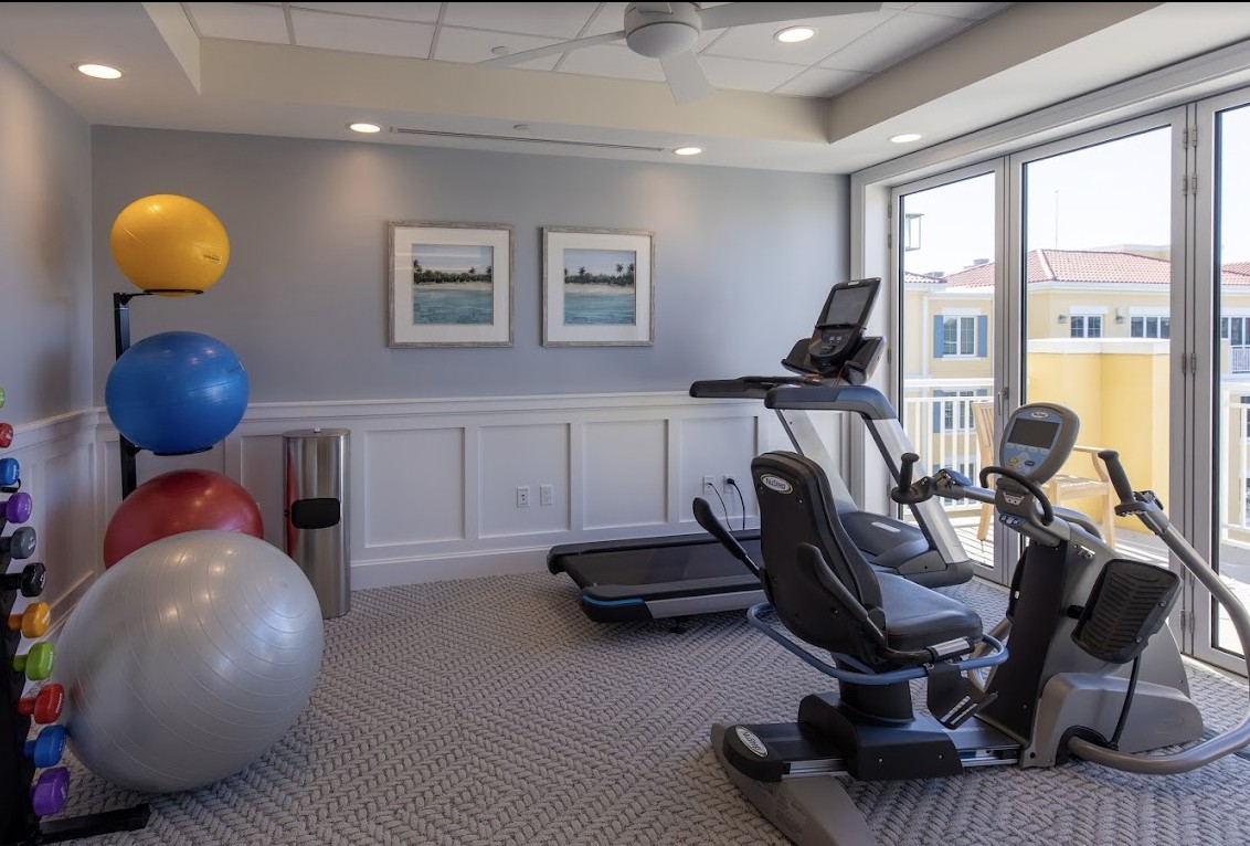 A small fitness room featuring a treadmill, stationary bike, and exercise balls.