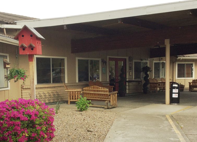 A welcoming building entrance featuring benches and colorful flowers.