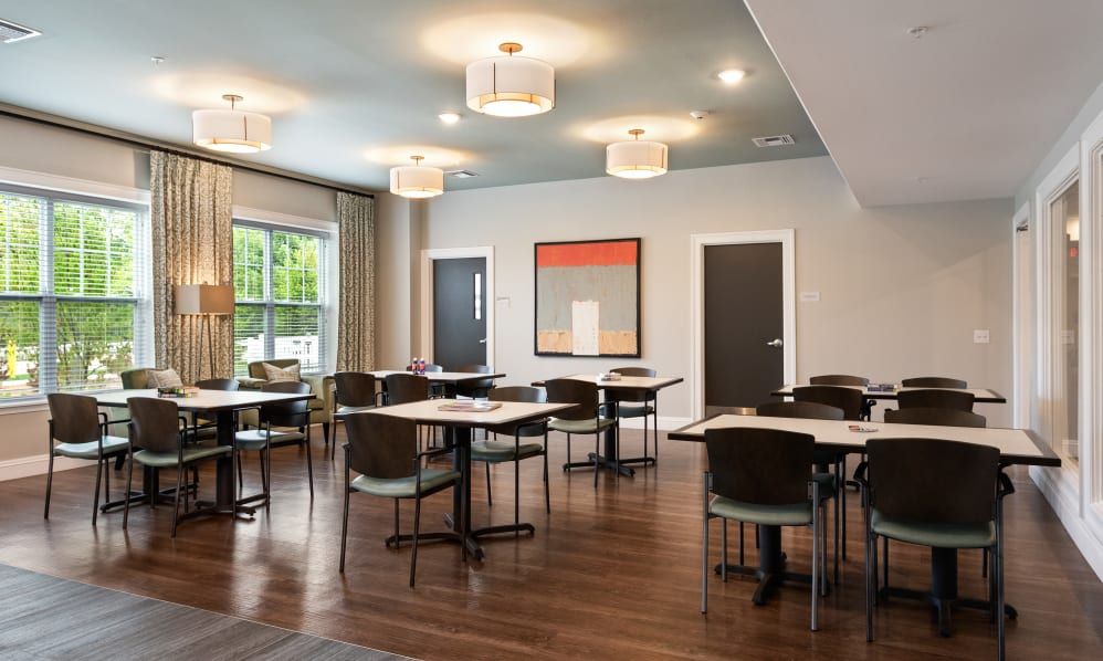 A modern dining room with neatly arranged tables and chairs, featuring contemporary lighting and artwork.