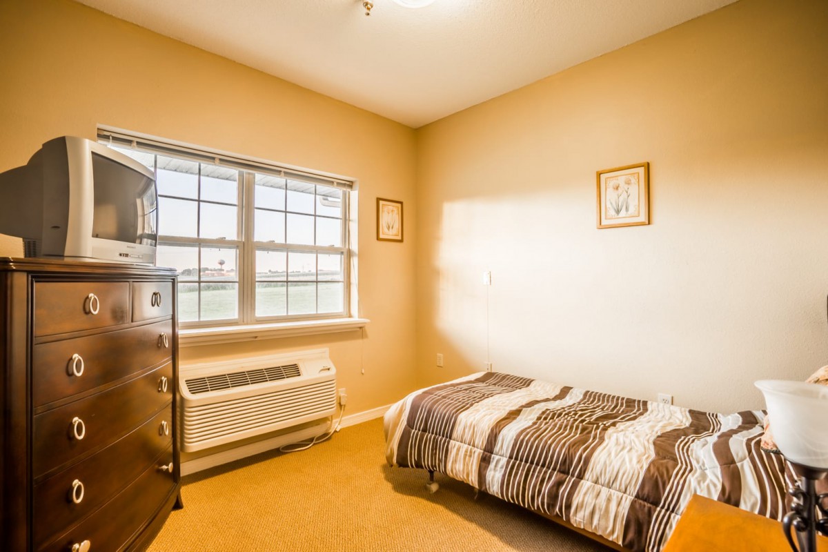 A cozy bedroom with a single bed and ample natural light from the window.