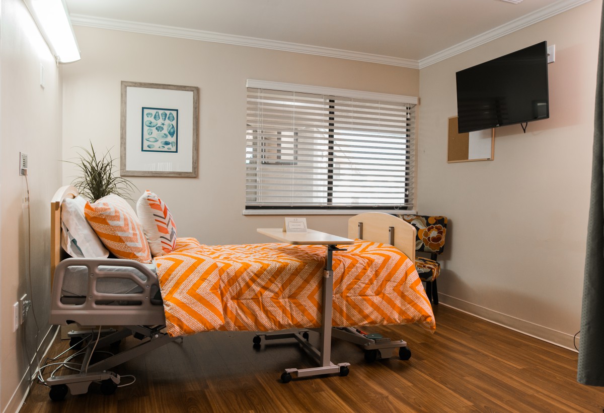 A cozy hospital room with a bed, TV, and window.