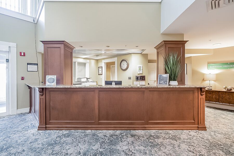 A well-lit reception area with a wooden desk and decorative plants.