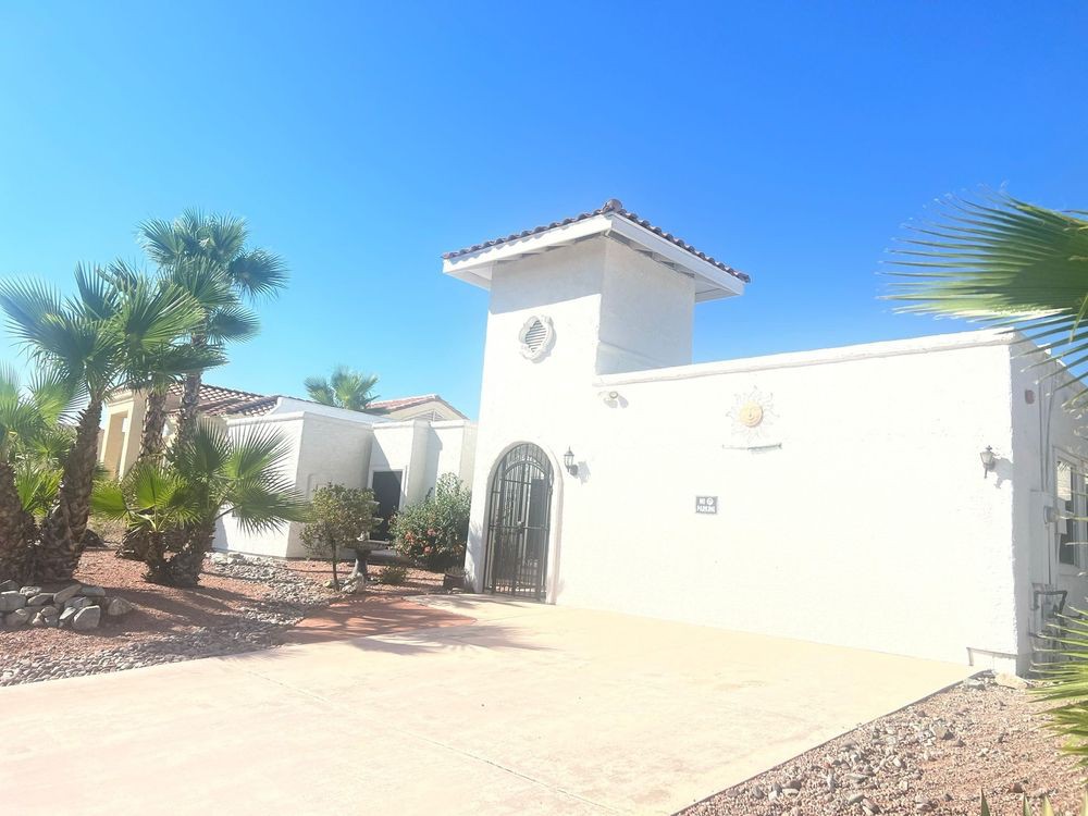 A Mediterranean-style house with white walls and palm trees under a clear blue sky.