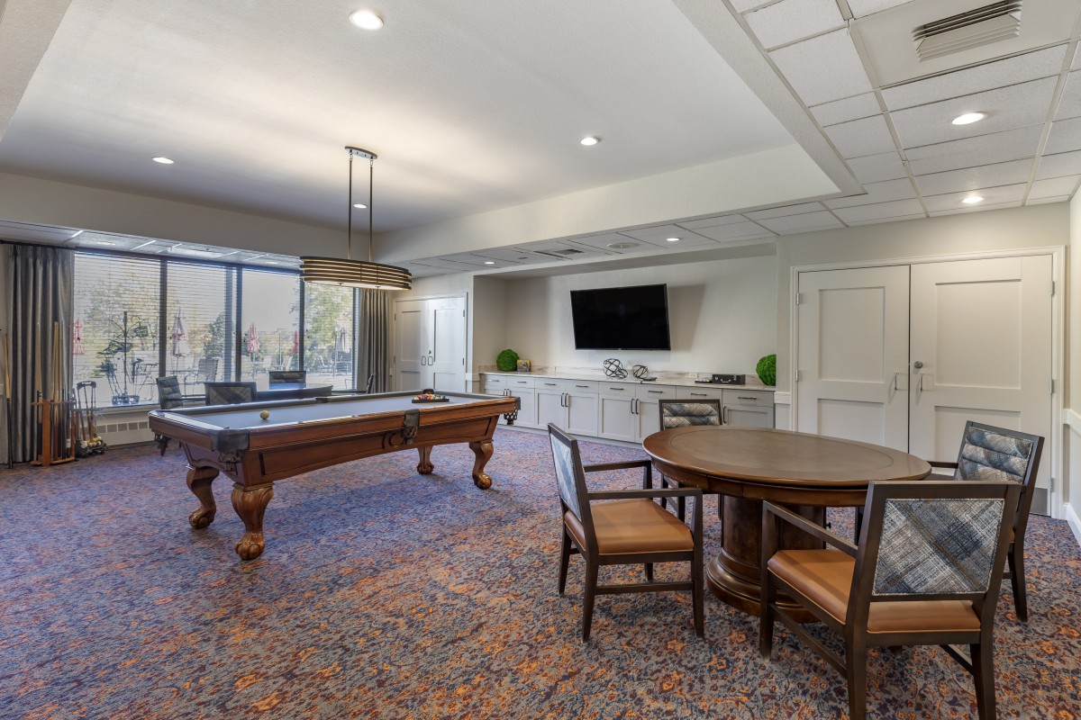 A modern game room featuring a billiards table, a television, and comfortable seating.