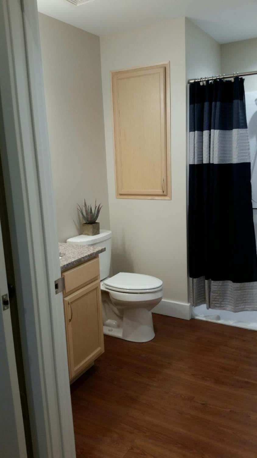 A clean and modern bathroom with a toilet, wooden cabinet, and striped shower curtain.