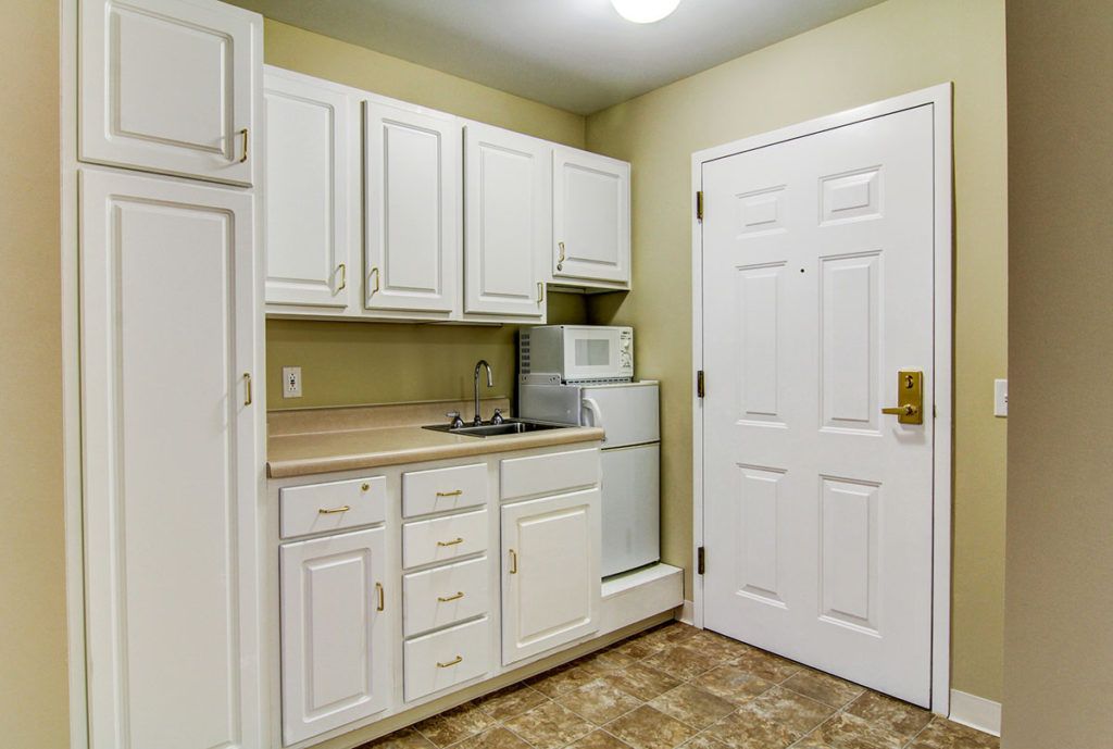 A small kitchen area featuring white cabinets, a microwave, and a mini refrigerator.