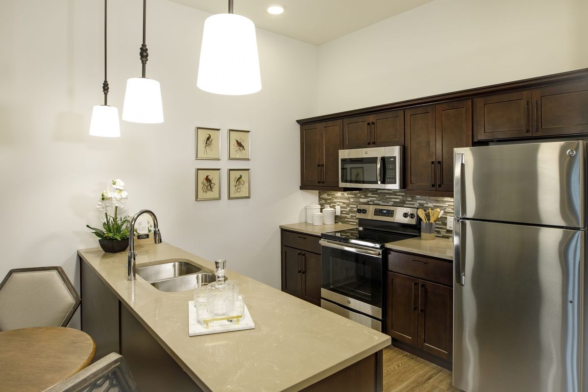 A modern kitchen featuring wooden cabinets, stainless steel appliances, and elegant pendant lighting.