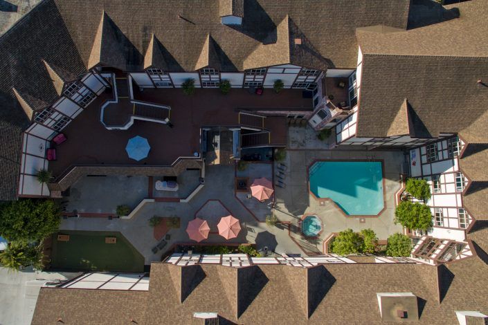 Aerial view of a building with a pool and patio umbrellas.