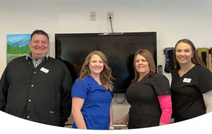A group of three people smiling indoors in front of a television.